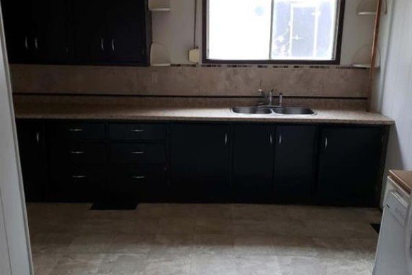 Kitchen with black cabinets, beige tiled backsplash, tan countertop, and a double sink. - 605 Railway Avenue, Trochu