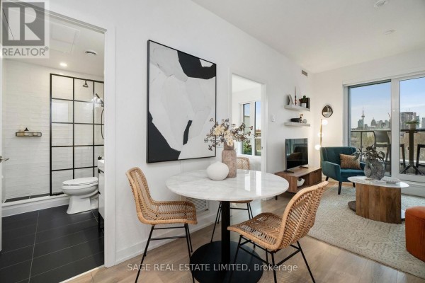 Hallway with a desk and shelf unit, leading towards the kitchen and an open doorway. - 606 - 150 Logan Avenue, Toronto