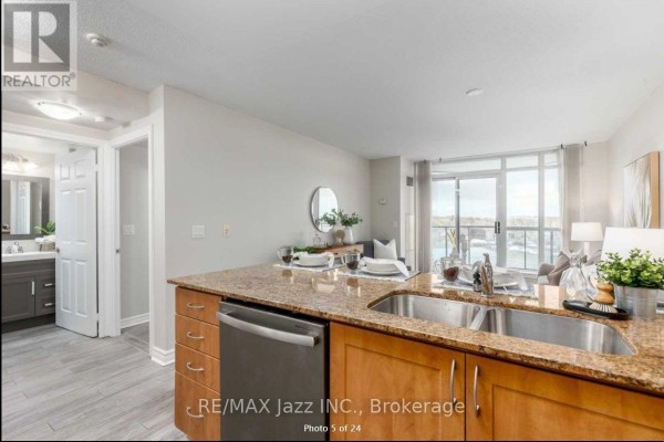 Kitchen with granite countertop, stainless steel dishwasher, and view of the living area and balcony. - 606 - 340 Watson Street W, Whitby
