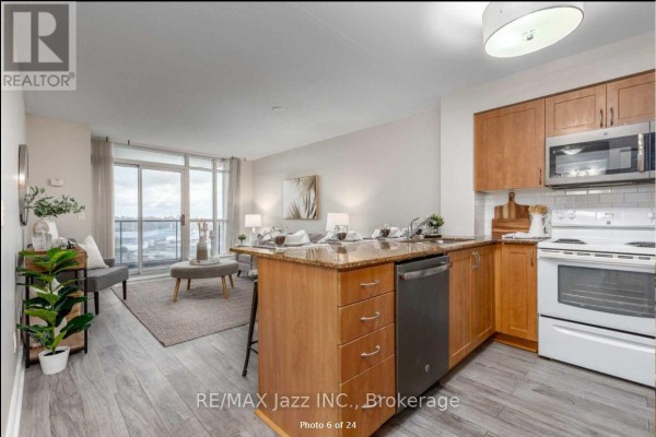 Open concept living and kitchen area with a large window overlooking the city and balcony. - 606 - 340 Watson Street W, Whitby