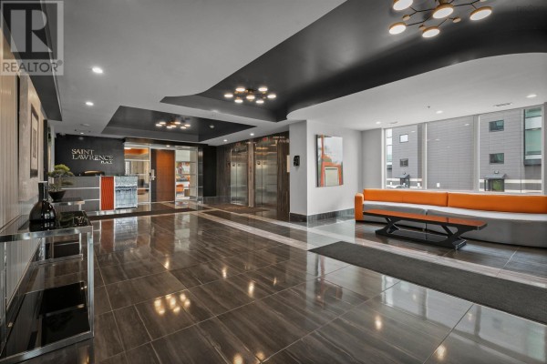 Apartment building lobby featuring polished tile floors, elevators, and bright orange seating. - 606 3471 Dutch Village Road, Halifax