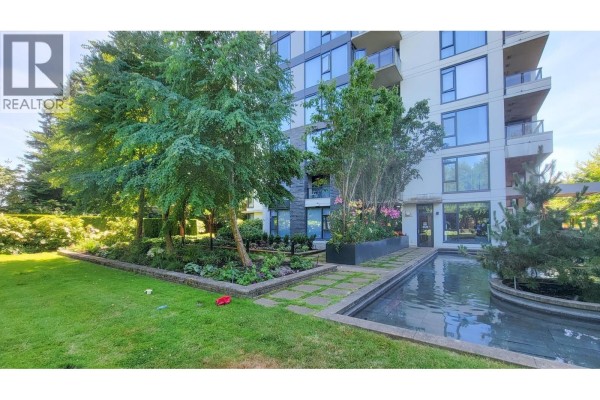 Exterior building view with surrounding greenery, garden beds, and a reflecting pool. - 606 5868 Agronomy Road, Vancouver