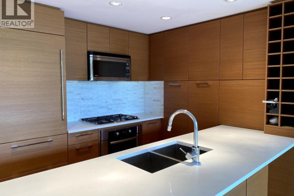 Contemporary kitchen with light wood cabinets, white countertop, gas stovetop, and island sink. - 606 5868 Agronomy Road, Vancouver