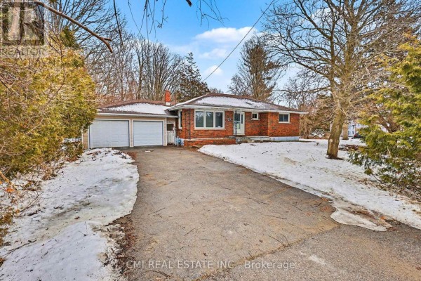 Driveway view of the bungalow with snow on the sides and trees. - 606 Glen Miller Road, Quinte West