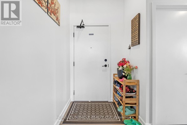 Interior hallway with white walls, a white door, shoe rack, and decorative wall art. - 607 - 20 Tubman Avenue, Toronto
