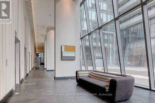 A modern lobby with dark tile floors, elevators, and a contemporary sofa. - 607 - 42 Charles Street, Toronto