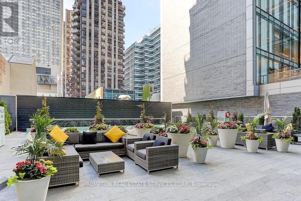 An outdoor seating area with wicker furniture, planters, and a water feature. - 607 - 42 Charles Street, Toronto