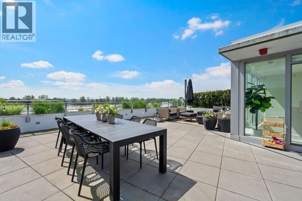 Open concept living area with kitchen, dining console, and balcony access. - 607 3438 Sawmill Crescent, Vancouver