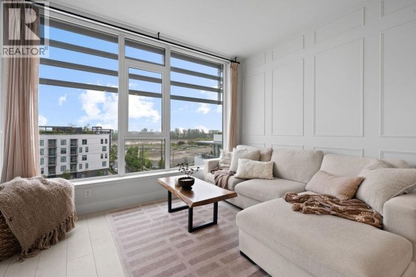 Living room with sectional sofa, coffee table, and large window with city view. - 607 3438 Sawmill Crescent, Vancouver