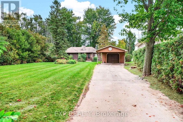 View of the cottage from the driveway, showing the entrance and a detached garage. - 607 Duclos Point Road, Georgina