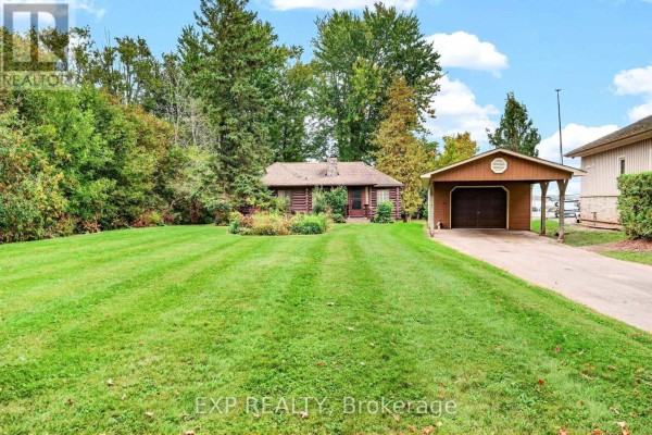 Front view of the cottage with a well-maintained lawn and surrounding trees. - 607 Duclos Point Road, Georgina