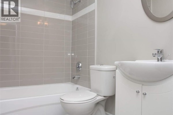 Bathroom with a bathtub, toilet, vanity, and beige tiled shower walls. - 607 Heritage Drive Unit# 401, Kitchener