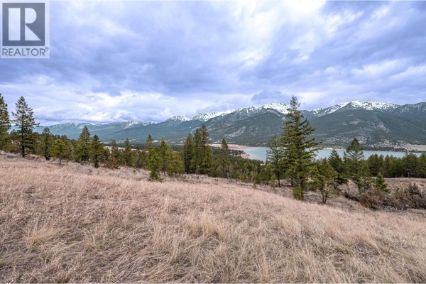 View of a valley with farmland, forested hills, a highway, and snow-dusted mountains. - 6079 93/95 Highway, Fairmont Hot Springs