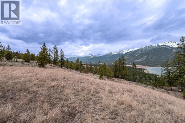 Drone shot showing a highway running alongside a wide, calm lake with forested mountains beyond. - 6079 93/95 Highway, Fairmont Hot Springs