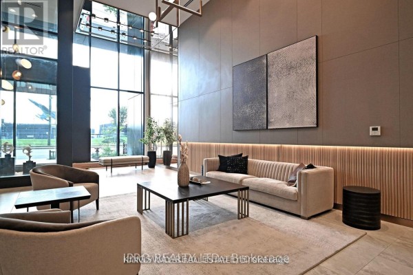 Apartment building lobby with beige sofa, chairs, and a dark coffee table. - 608 - 1100 Sheppard Avenue W, Toronto