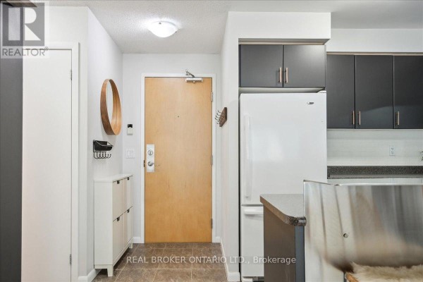 Hallway with a dark accent wall, shelves, and storage cubbies leading to a bathroom. - 608 - 185 Legion Road N, Toronto
