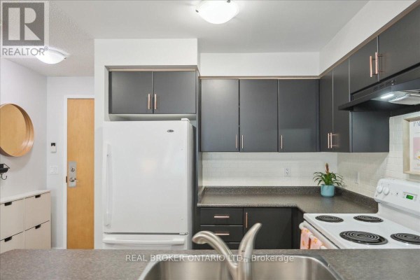 Dining area with a wooden table, brown chairs, and a black accent wall with artwork. - 608 - 185 Legion Road N, Toronto