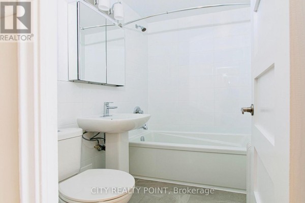Compact bathroom with a white pedestal sink, toilet, bathtub, and a mirrored medicine cabinet. - 608 - 2 Grandstand Place, Toronto