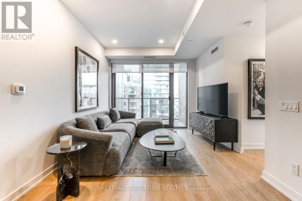 Bright bedroom with large window, minimalist decor, and a black upholstered bed. - 608 - 35 Parliament Street, Toronto