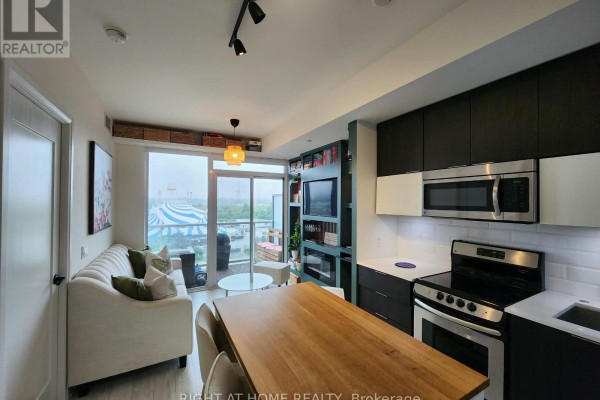 Apartment interior showing living space, dining table, and modern kitchen. - 608 - 56 Annie Craig Drive, Toronto