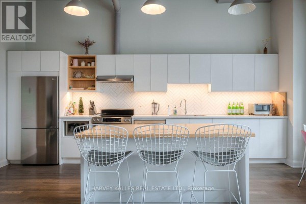 White cabinetry and a butcher block island with wire stools in a minimalist kitchen. - 608 - 700 King Street W, Toronto