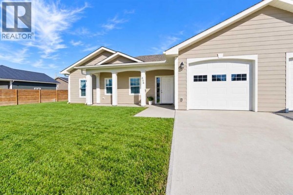Front exterior of a beige duplex with a white front door and attached garage. - 608 10 Avenue W, Barnwell