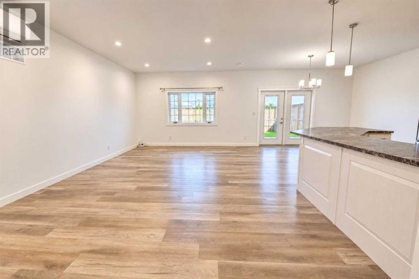 Open-concept living and dining area with white walls and wood-look flooring. - 608 10 Avenue W, Barnwell