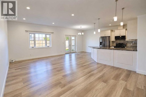 Kitchen and dining area with white cabinets, granite countertops, and stainless steel appliances. - 608 10 Avenue W, Barnwell