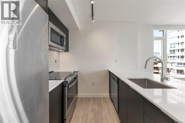 Interior view of a walk-in closet with white shelves, drawers, and hanging space. - 608 845 Johnson St, Victoria