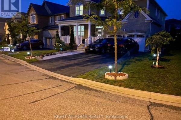 Evening view of houses with driveways, cars, and illuminated lawns. - 608 Wettlaufer (bsmnt) Terrace, Milton