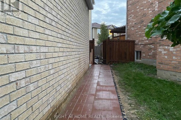 Red brick pathway along beige brick wall and wooden fence. - 608 Wettlaufer (bsmnt) Terrace, Milton