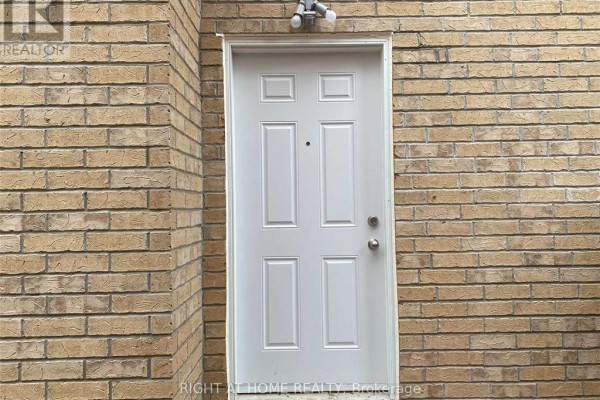 White paneled door on a beige brick wall with a security light. - 608 Wettlaufer (bsmnt) Terrace, Milton