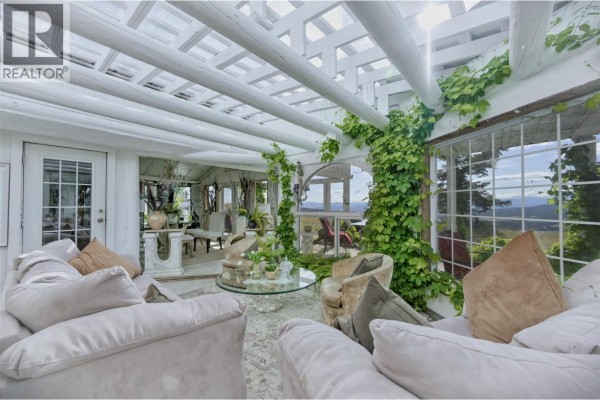 Sunroom with white wooden pergola ceiling, plants, and couches. - 6080 Highway 3, Bridesville