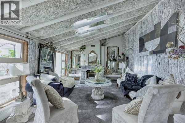 Living room with stone textured walls, fireplace, and multiple seating areas. - 6080 Highway 3, Bridesville