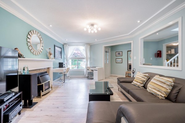 Living room featuring a fireplace, large windows, a desk area, and a sectional sofa. - 6081 W Boundary Drive, Surrey