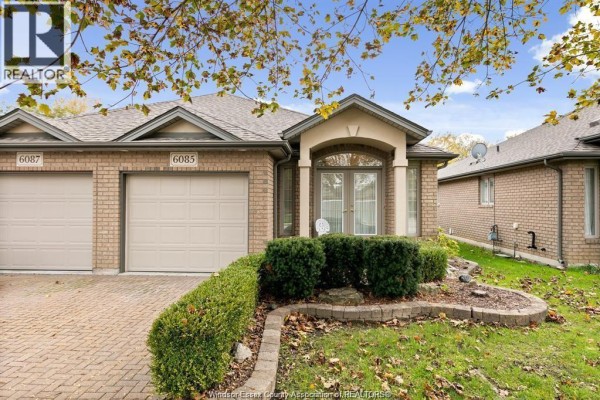Front exterior of a beige brick townhouse with a garage and manicured landscaping. - 6085 Natalie Court, Lasalle