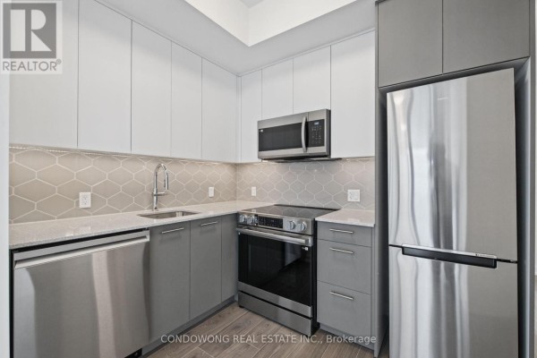 Apartment kitchen featuring grey and white cabinets, a stainless steel stove, microwave, and refrigerator. - 609 - 30 Francis Street S, Kitchener