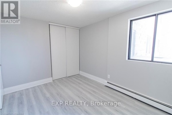Bedroom with grey walls, a large window, and a white bi-fold closet door. - 609 - 4422 Huron Street, Niagara Falls