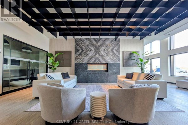 Lounge area with fireplaces, sofas, armchairs, and large windows in a modern building. - 609 - 8020 Derry Road, Milton