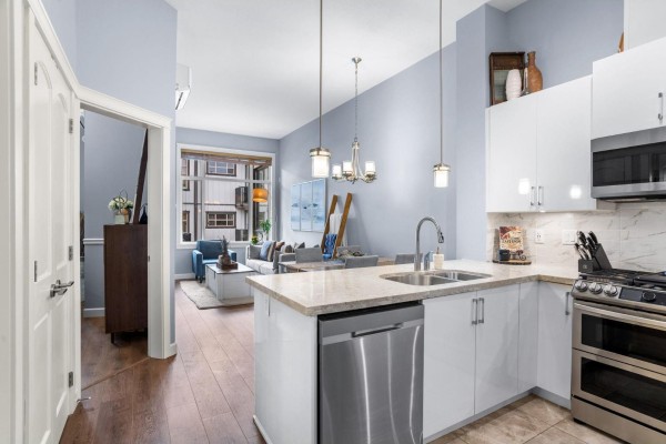 Open concept living area with a kitchen island, dining area, and living room beyond. - 609 20328 86 Avenue, Langley