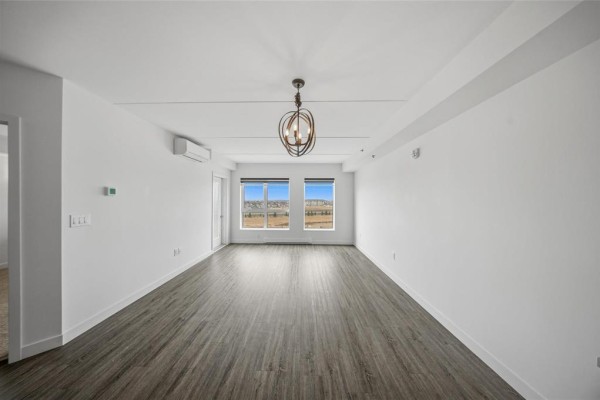 Long interior hallway in an apartment building with multiple doors and wood-look flooring. - 609 300 Centre Street, Winnipeg