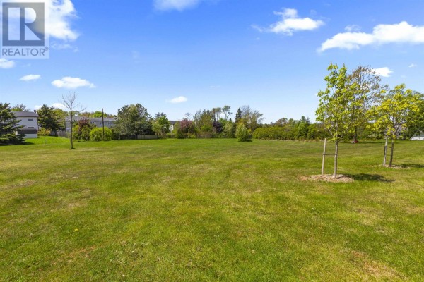 Expansive green lawn with scattered trees and a distant view of houses under a bright blue sky. - 609-611 Queen Street, Charlottetown