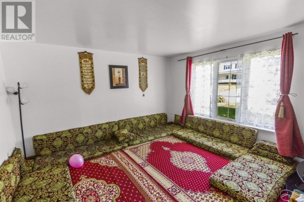 Living room with floor-level seating, patterned cushions, rugs, and a window with sheer curtains. - 609-611 Queen Street, Charlottetown