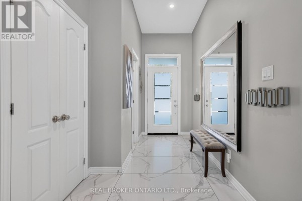 Hallway with light grey walls, white doors, a marble tile floor, and a long bench with a mirror. - 609 Egret Way, Ottawa