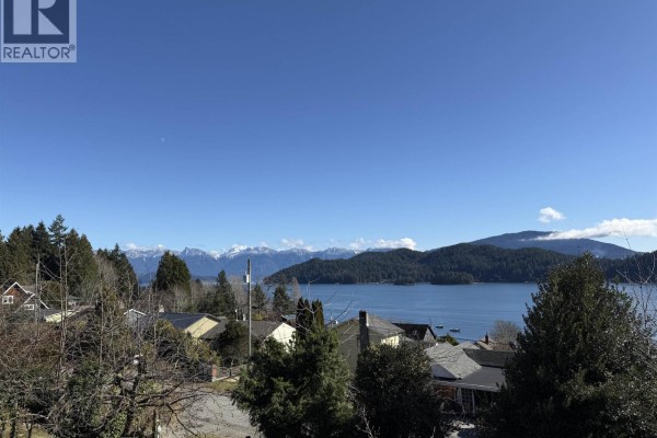 View of houses, trees, water, and snow-capped mountains under a clear blue sky. - 609 Glen Road, Gibsons