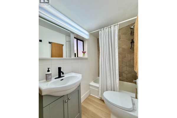 Small bathroom with a white sink, gray vanity, toilet, and a tiled shower area. - 609 Glen Road, Gibsons