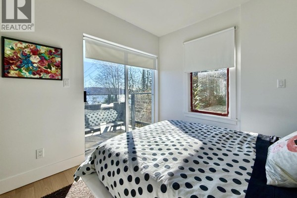 Bedroom with a white duvet, black polka dots, and a sliding glass door leading outside. - 609 Glen Road, Gibsons