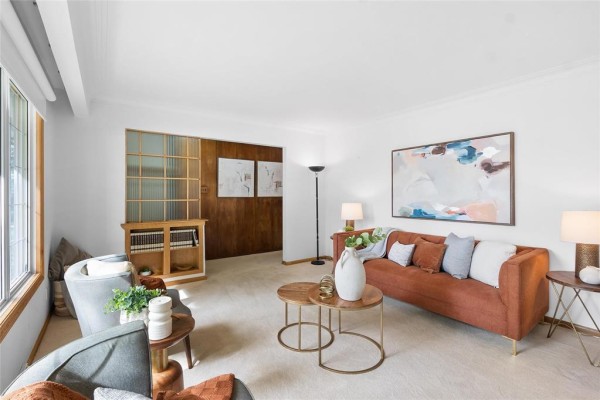 Living room with white walls, plush carpet, wood paneling, and abstract art above a sofa. - 609 Mcleod Avenue, Winnipeg