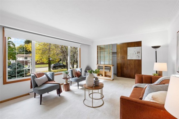 Living room featuring a large picture window, seating area, and a wood paneled divider. - 609 Mcleod Avenue, Winnipeg