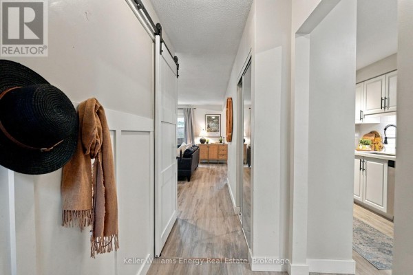 Hallway with a sliding barn door on the left, leading to a living area visible in the distance. - 61 - 155 Glovers Road, Oshawa